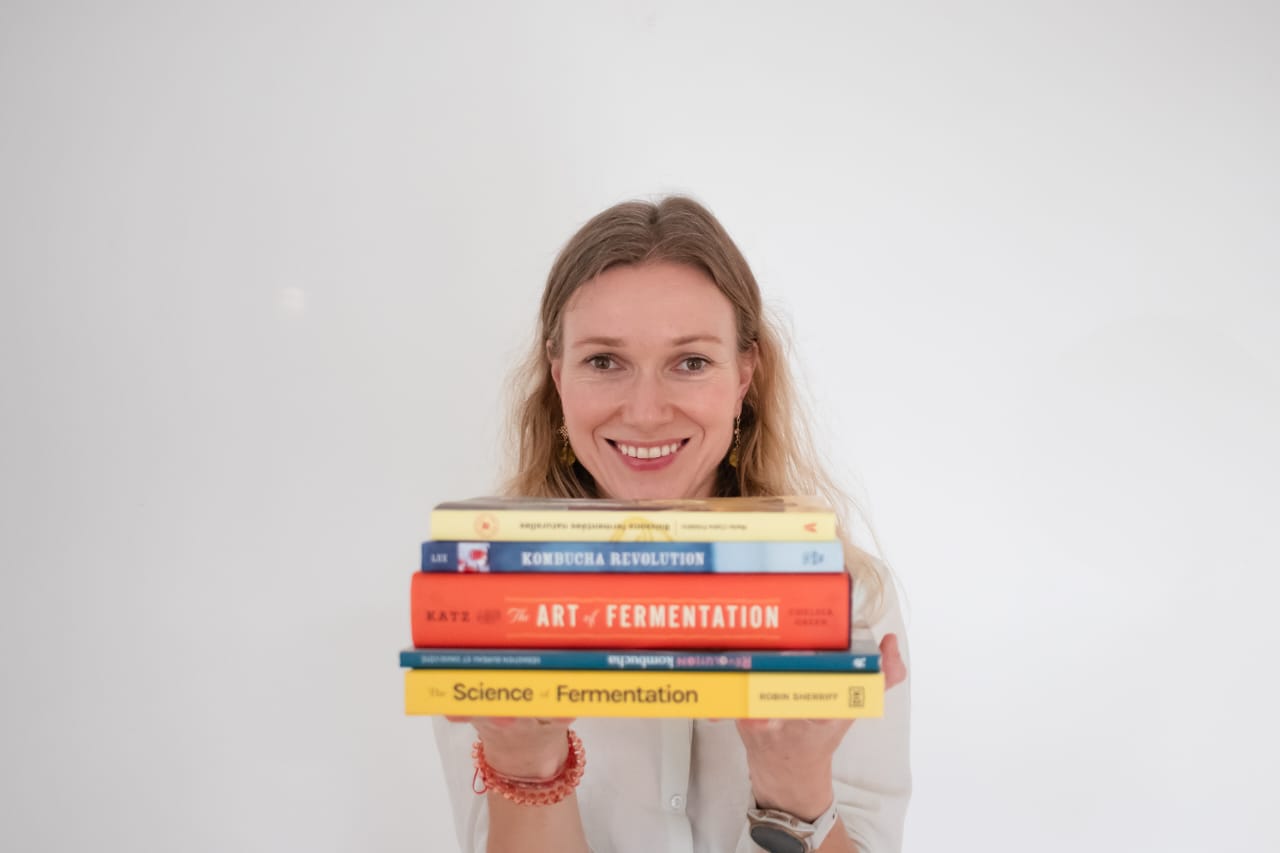 Founder of Au passage holding a stack of fermentation books